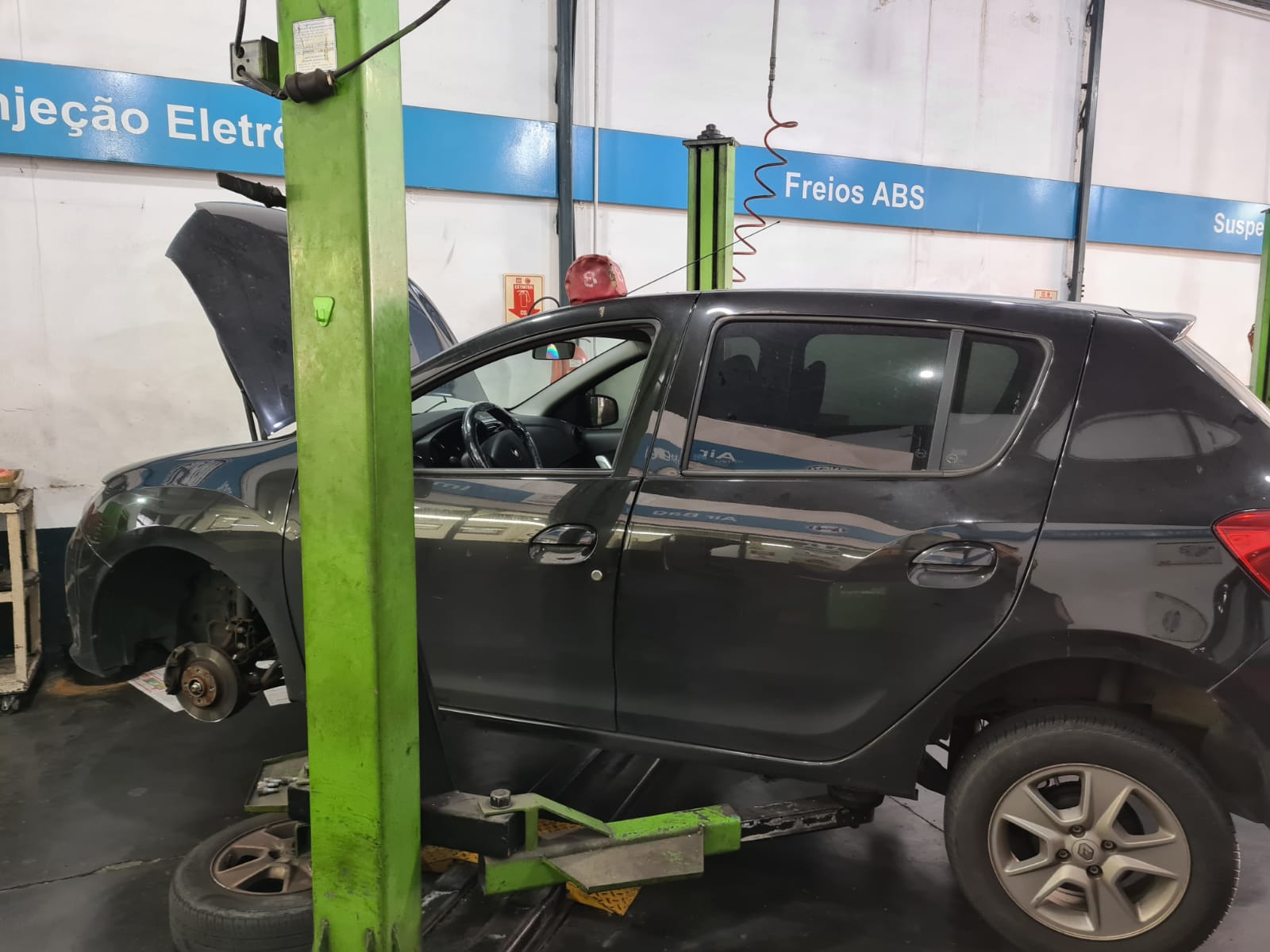 Carro no elevador sendo desmontado